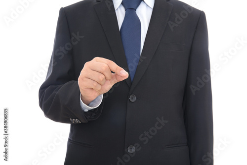 A male in a black suit makes a pinch gesture with his right hand