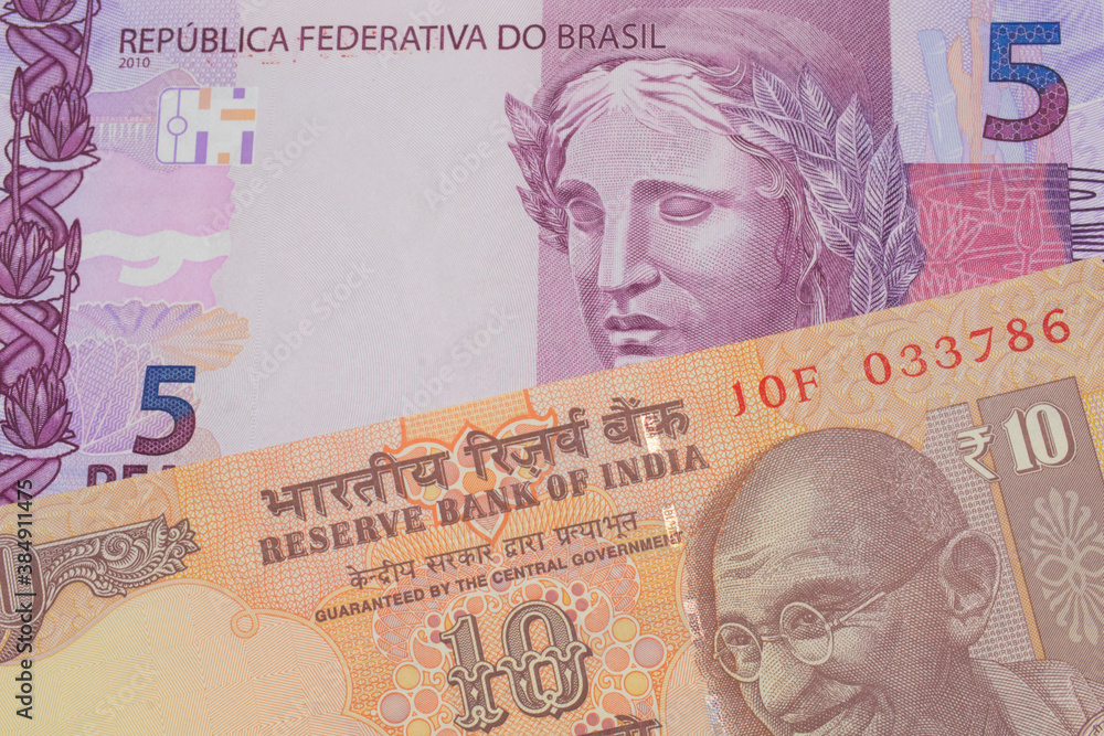 Fototapeta premium A macro image of a orange ten rupee bill from India paired up with a pink and purple five real bank note from Brazil. Shot close up in macro.