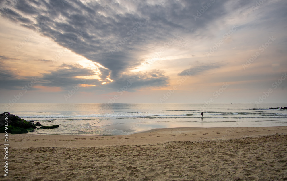 Asbury Park, NJ / United States - Oct. 11, 2020:  Sunrise at Asbury Park's beach, with a fisherman in the surf