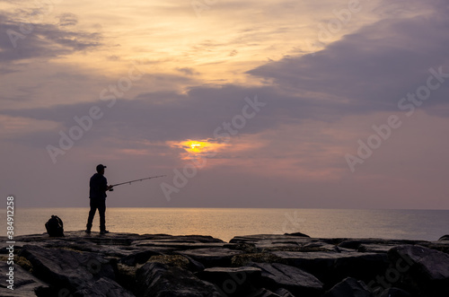 Asbury Park, NJ / United States - Oct. 11, 2020: a landscape of a man fishing off the the jetty at Asbury Park in the morning hours.