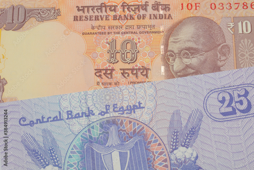 Fototapeta premium A macro image of a orange ten rupee bill from India paired up with a blue twenty five piastre bank note from Egypt. Shot close up in macro.