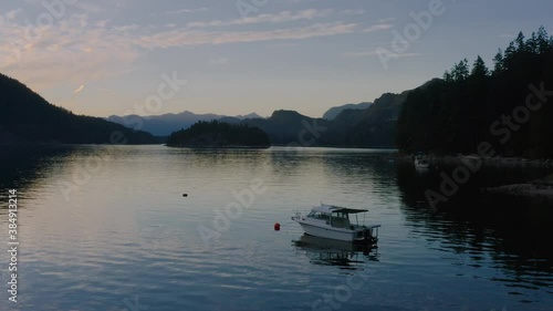 A White Speedboat Anchored At The Sechelt Inlet - Pacific Ocean Fjord On The Sunshine Coast Near Egmont, British Columbia, Canada At Sunset. - aerial drone shot photo