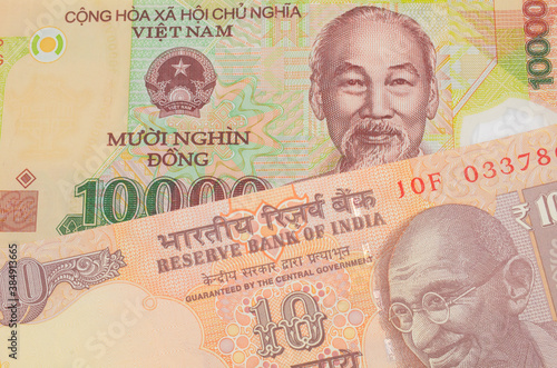 A macro image of a orange ten rupee bill from India paired up with a colorful, plastic ten thousand dong note from Vietnam.  Shot close up in macro.