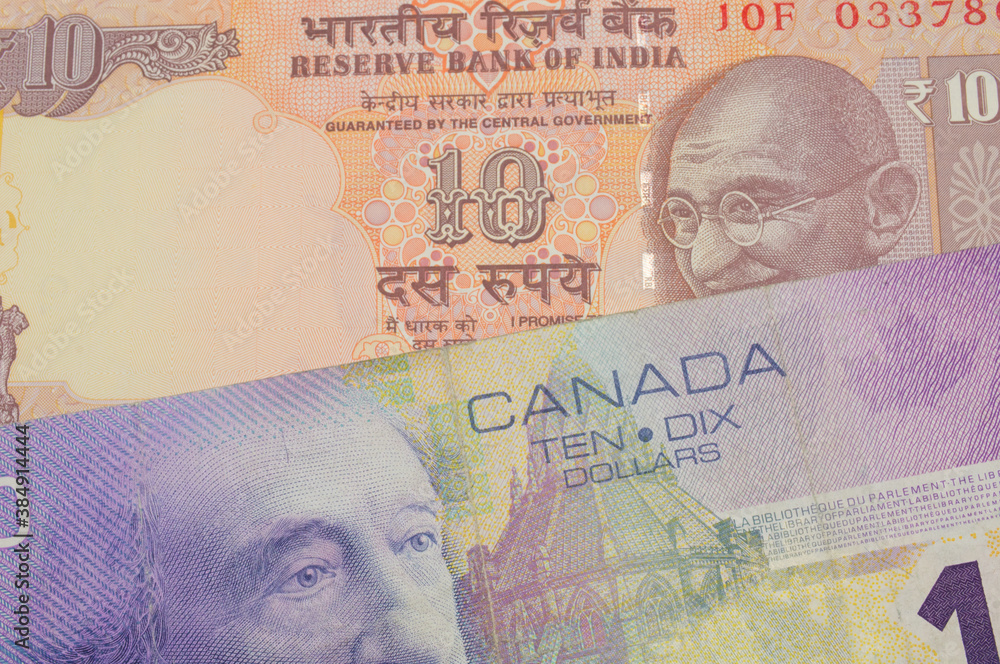 Fototapeta premium A macro image of a orange ten rupee bill from India paired up with a purple ten dollar bill from Canada. Shot close up in macro.