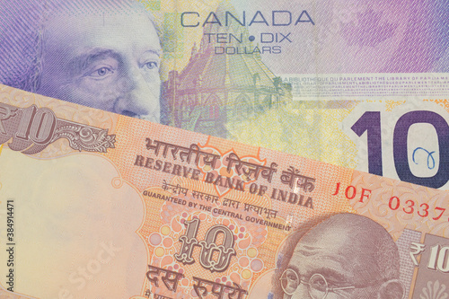 A macro image of a orange ten rupee bill from India paired up with a purple ten dollar bill from Canada.  Shot close up in macro.