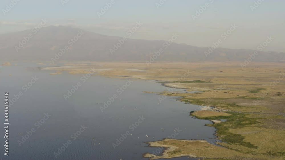 Aerial view of Tanzania. Drone flying over the shoreline of the salt lake Natron in the savannah with a background on the volcano Ol Doinyo Lengai . Aerial view of Tanzania. Aerial view of Tanzania. Drone flying over the shoreline of the salt lake Natron in the savannah with a background on the volcano Ol Doinyo Lengai . Aerial view of Tanzania.