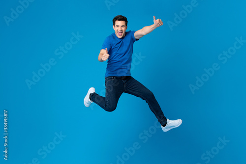 Fotografie, Obraz Smiling handsome American man joyfully jumping and doing double thumbs up gestur