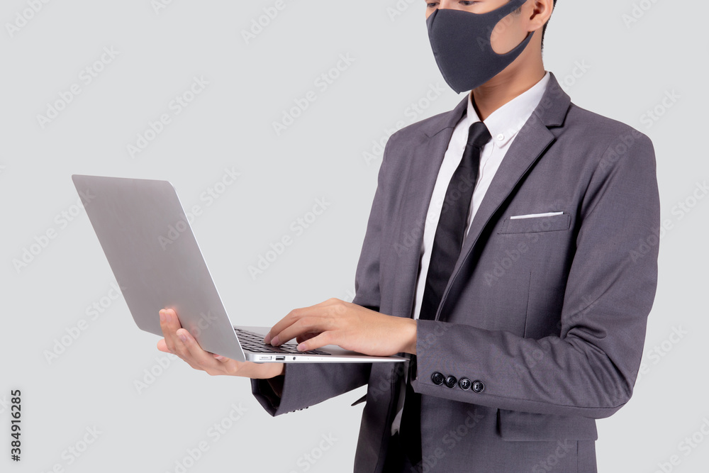 Young asian business man in face mask using laptop computer isolated on white background, quarantine and epidemic covid-19, businessman work from home for health, social distancing, new normal. Young asian business man in face mask using laptop computer isolated on white background, quarantine and epidemic covid-19, businessman work from home for health, social distancing, new normal.