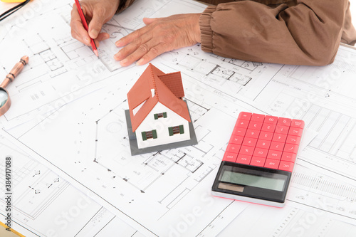 Close-up shot of the designer using a pencil to modify the architectural design on the drawing
