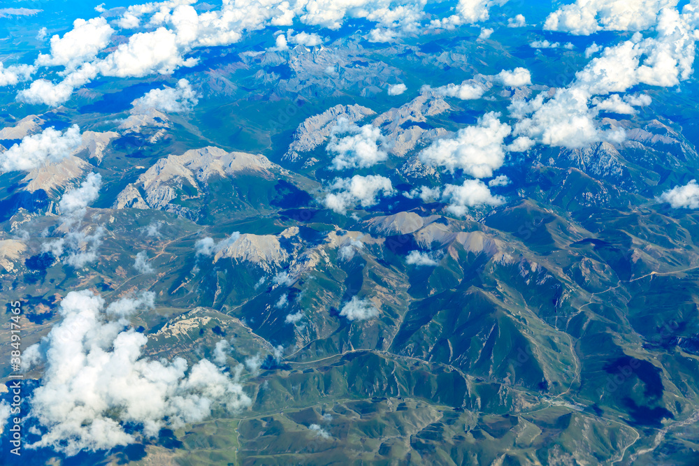 Aerial view above the clouds and mountain peaks on a sunny day.mountain view from airplane. Aerial view above the clouds and mountain peaks on a sunny day.mountain view from airplane.