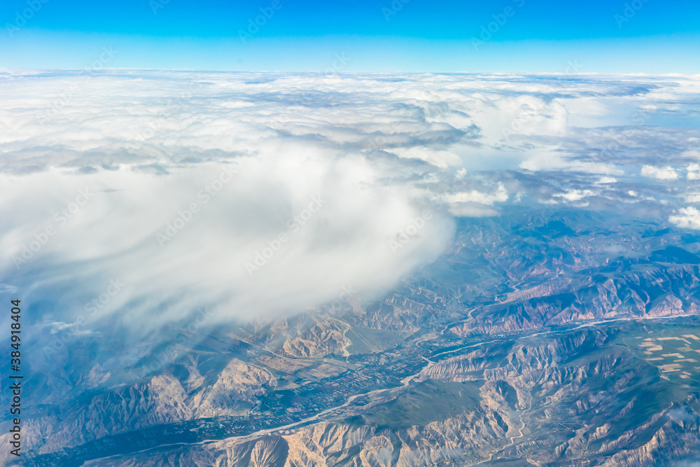 Fototapeta premium Aerial view above the clouds and mountain peaks on a sunny day.mountain view from airplane.