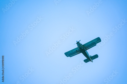Retro green biplane plane in the blue sky