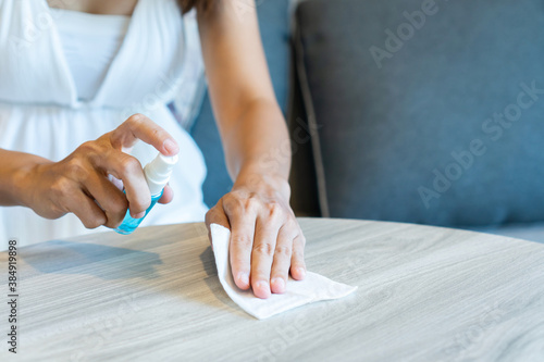 Woman hand cleaning desk in hotel room with disinfectant wet wipe and alcohol spray. Concept of disinfecting surfaces from bacteria or viruses. Close up