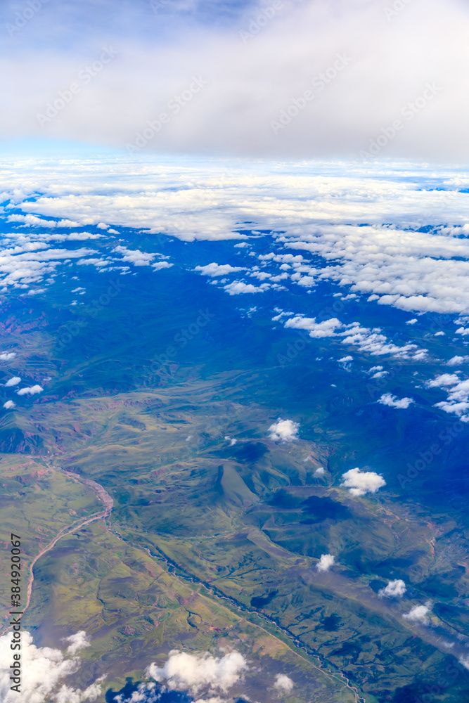 Aerial view above the clouds and mountain peaks on a sunny day.mountain view from airplane. Aerial view above the clouds and mountain peaks on a sunny day.mountain view from airplane.