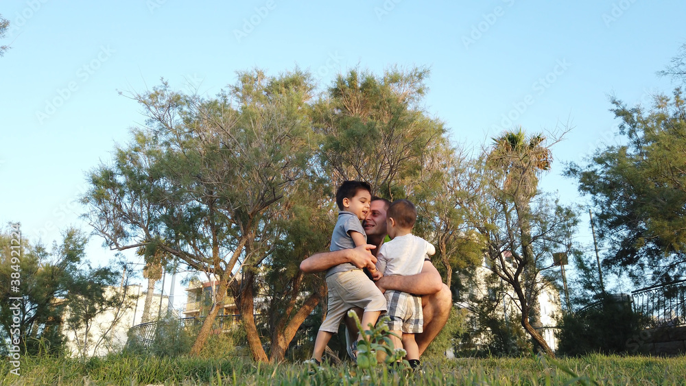 Young father hugging his sons in the park. Happy family concept. High quality photo Young father hugging his sons in the park. Happy family concept. High quality photo