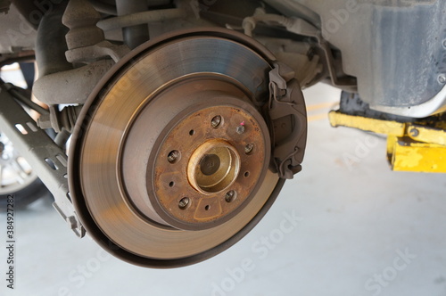 Close-up disc brake rear of a wheeled car for inspection and repair.
