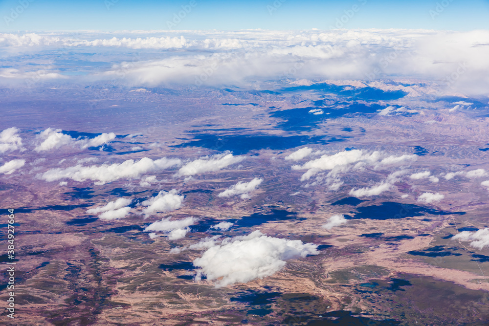 Obraz premium Aerial view above the clouds and mountain peaks on a sunny day.mountain view from airplane.