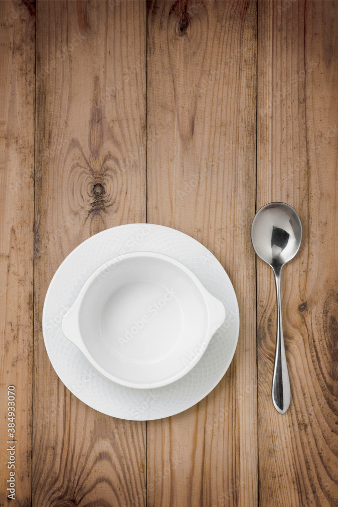 Empty white soup cup with spoon on a wooden table Empty white soup cup with spoon on a wooden table