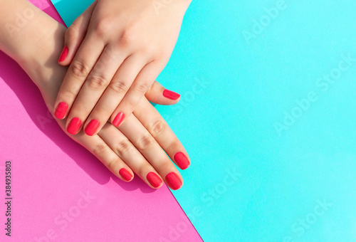 Female hands with manicure on blue and pink background.