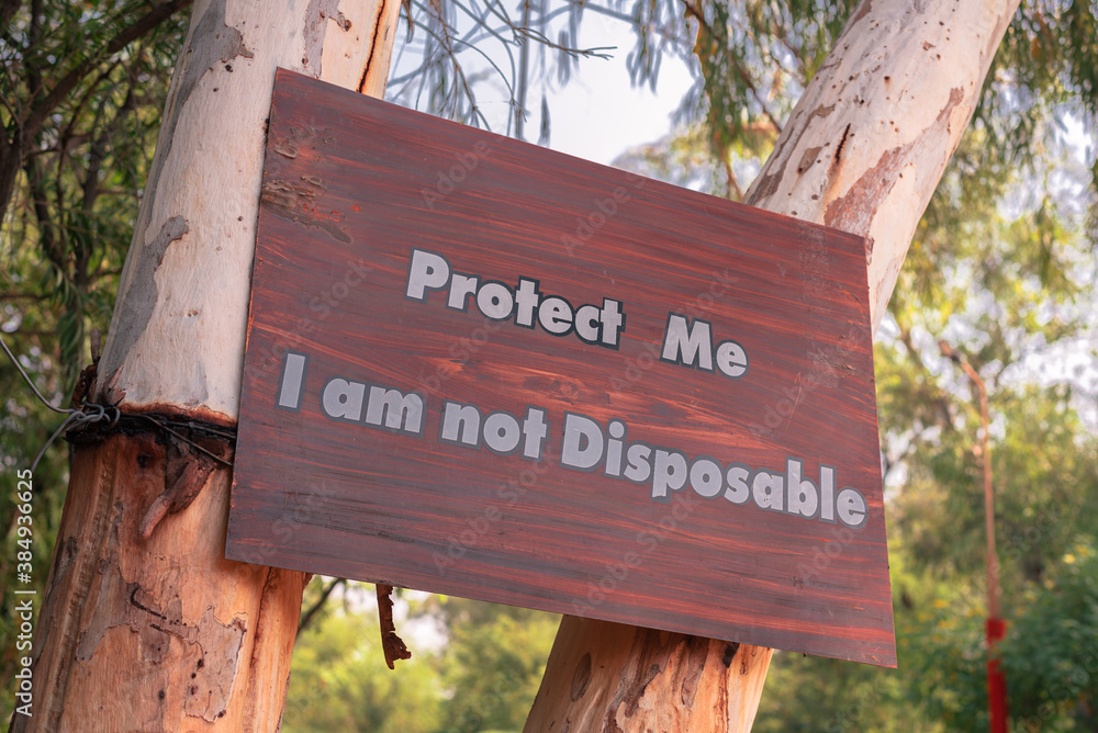 Fototapeta premium Protect me I am not disposable A sign board with message on a tree Save tree save planet Save nature save trees