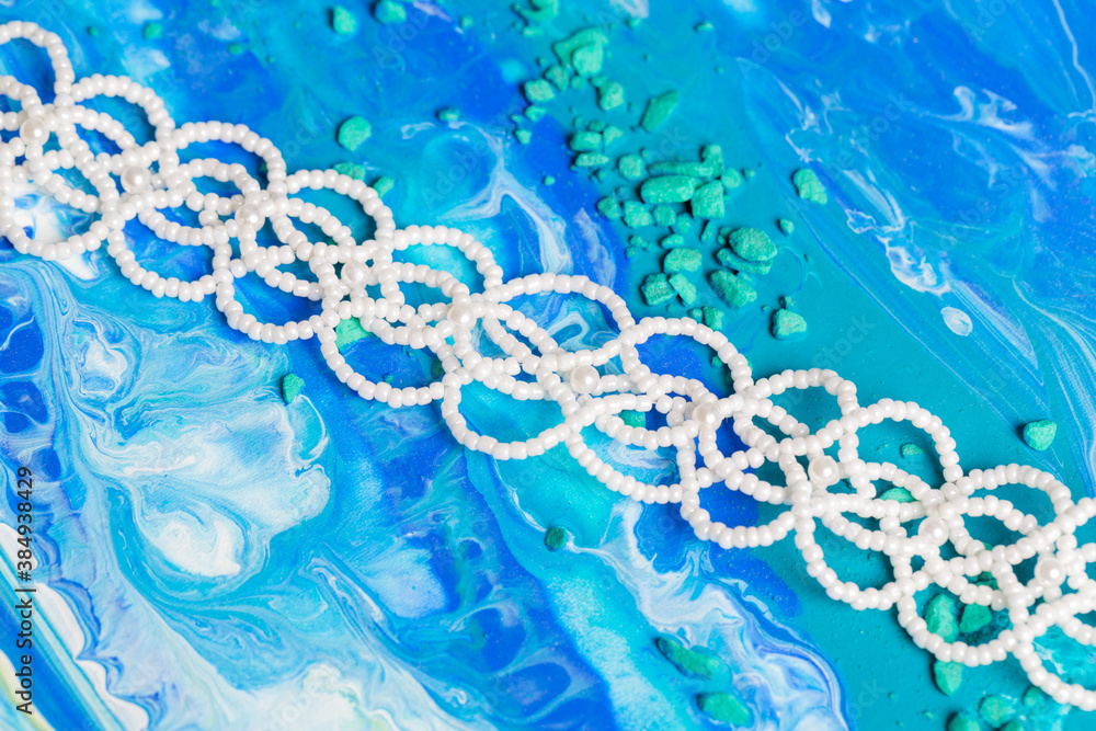 Handmade bracelet made of white beads on canvas with blue colors Handmade bracelet made of white beads on canvas with blue colors