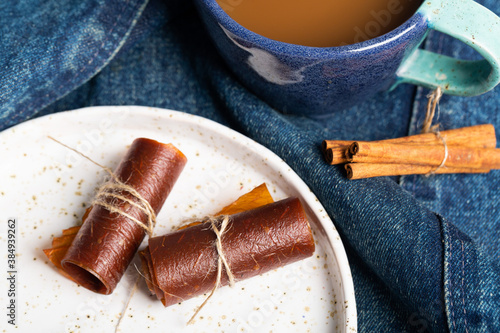 Fruit pastille on a porcelain plate on jeans with a jug of juice in the background and cinnamon photo