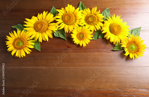 Beautiful bright sunflowers on wooden background, flat lay. Space for text