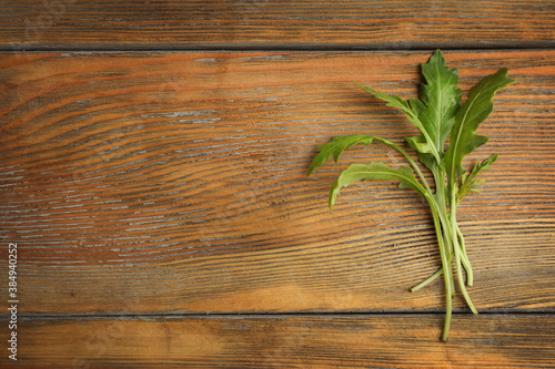 Fresh arugula on wooden table  flat lay. Space for text