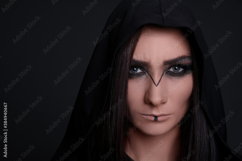 Mysterious witch in mantle with hood on black background, closeup. Space for text Mysterious witch in mantle with hood on black background, closeup. Space for text