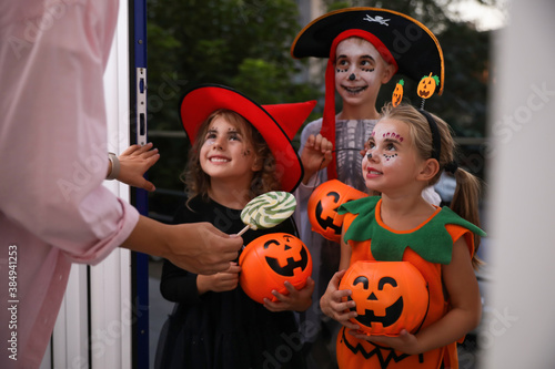 Cute little kids wearing Halloween costumes and trick-or-treating at doorway © New Africa