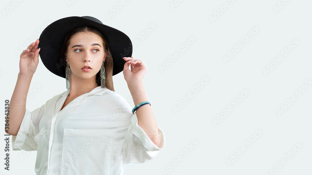 Trend fashion look. Glamorous outfit. Stylish woman in straw black hat vintage earrings white shirt. Isolated on neutral copy space. Boho model lifestyle. Advertising background Trend fashion look. Glamorous outfit. Stylish woman in straw black hat vintage earrings white shirt. Isolated on neutral copy space. Boho model lifestyle. Advertising background