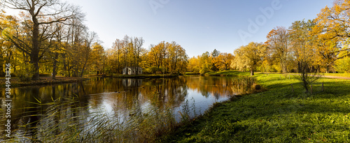 Panorama of the autumn landscape with a view of the lake and trees.