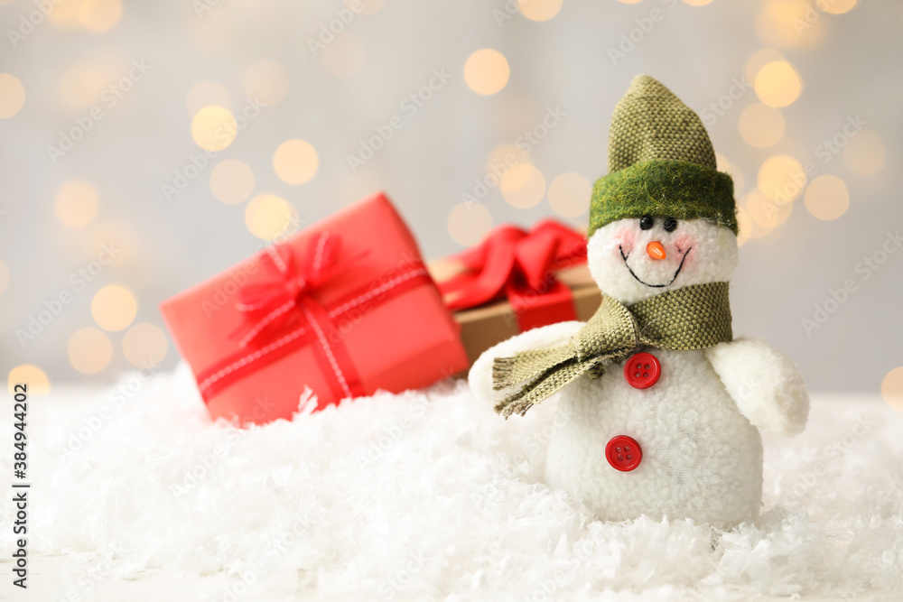 Snowman toy on snow against blurred festive lights, space for text. Christmas decoration Snowman toy on snow against blurred festive lights, space for text. Christmas decoration