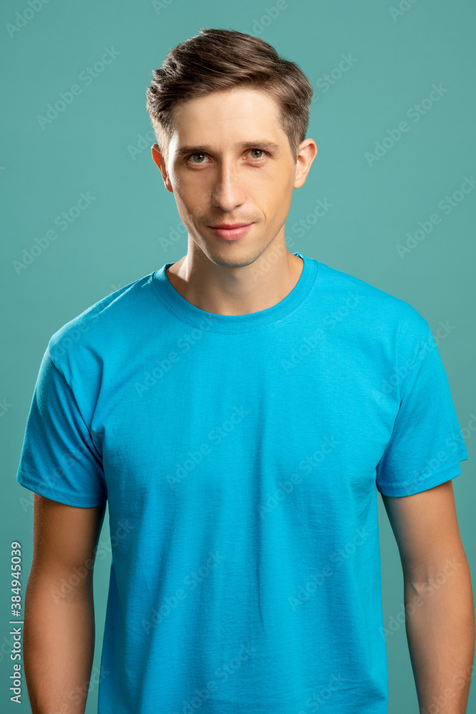 Obraz premium Confident man. Casual sportive look. Masculine charm. Young attractive smiling guy in t-shirt looking at camera isolated on blue.