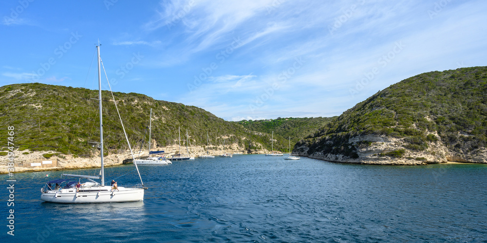 Panorama of the bay with mountains against blue sky with clouds. White yacht in the foreground. Copy space