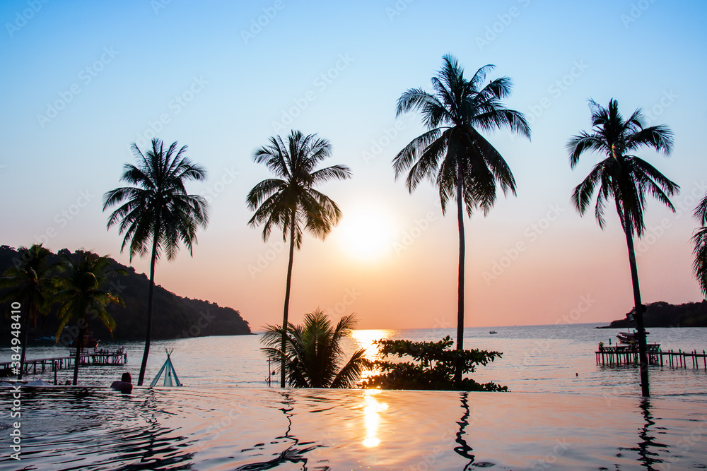 Sunset reflecting on the water surface foreground with coconut trees area ao bang bao at Koh kood island is a district of Trat Province. Thailand.