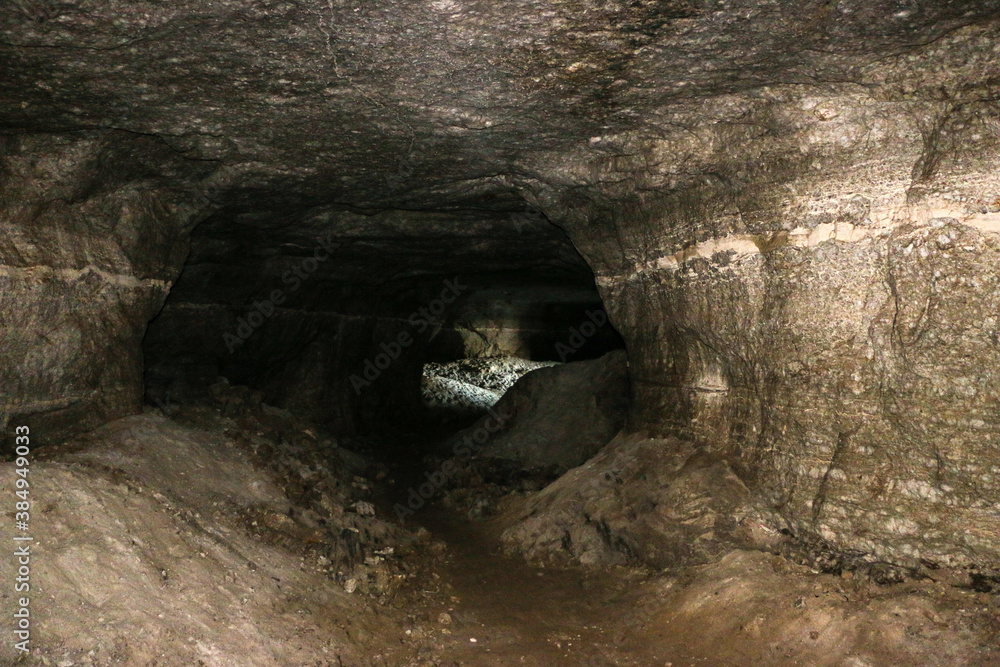 Obraz premium old abandoned galleries, adits, for extraction and processing of natural stone and gypsum cave. Dark eerie stone, quartz tunnels deep in earth. Various rocks, geological and speleological research.