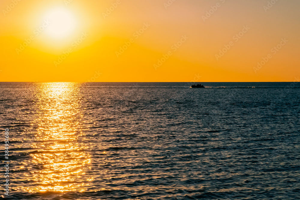 Beautiful sunset on the sea with golden sky and boat silhouette, great design for any purposes. Summer nature landscape. Travel concept background. Sea landscape.