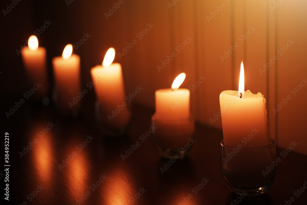 Fototapeta premium Candle light in Glass cup decoration in spa and christmas night party in Bokeh background. Holiday and Romantic love on valentines day Concept. Prayer and peace in Buddhism