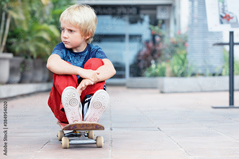 Little skater with skateboard have fun before children training class in skate park. Active family lifestyle, outdoor recreational activities on summer holidays in city. Kids sports and urban fashion. Little skater with skateboard have fun before children training class in skate park. Active family lifestyle, outdoor recreational activities on summer holidays in city. Kids sports and urban fashion.