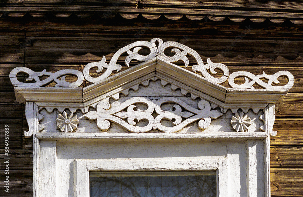 Fragment of the window of an old Russian wooden house from the times of the Russian Empire. There are carved decorations in the facade decor. Architecture of the European part of Russia (southern city