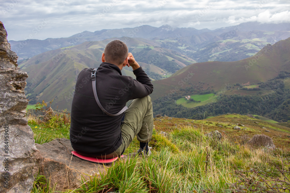 Man sitting on the top of Pyrenees mountains, France. Pause in travel. Tired pilgrim on Camino de Santiago. Lonely hiker in highlands. Active lifestyle. Freedom concept. Getting from it all concept. A