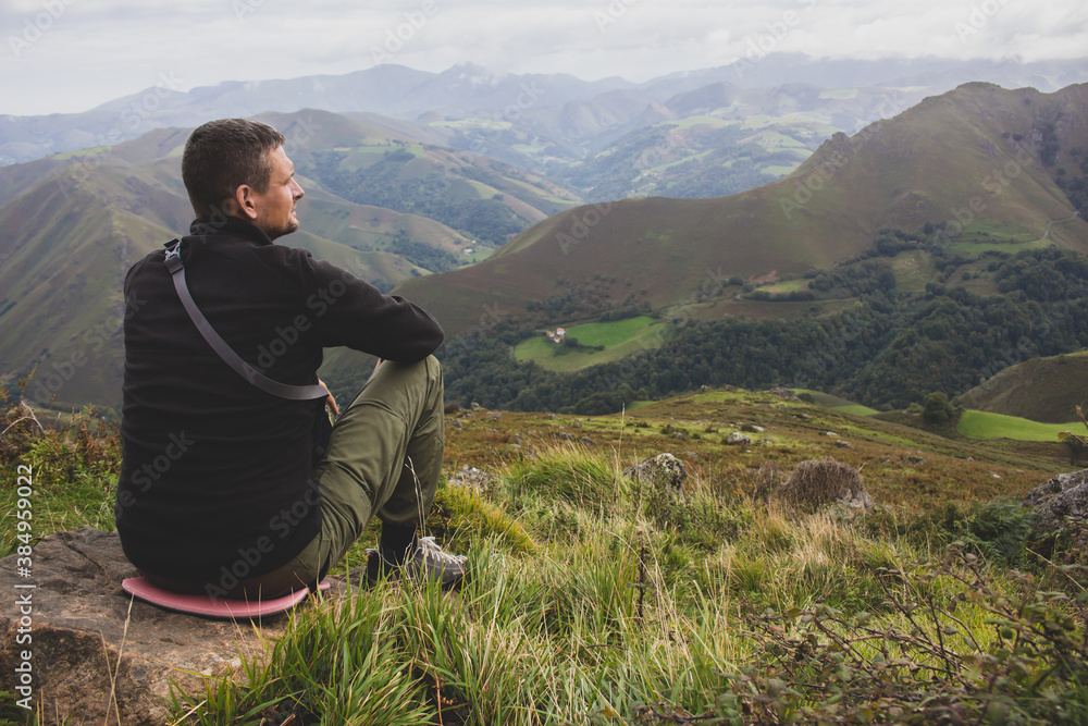 Man sitting on the top of Pyrenees mountains, France. Pause in travel. Tired pilgrim on Camino de Santiago. Lonely hiker in highlands. Active lifestyle. Freedom concept. Getting from it all concept. 