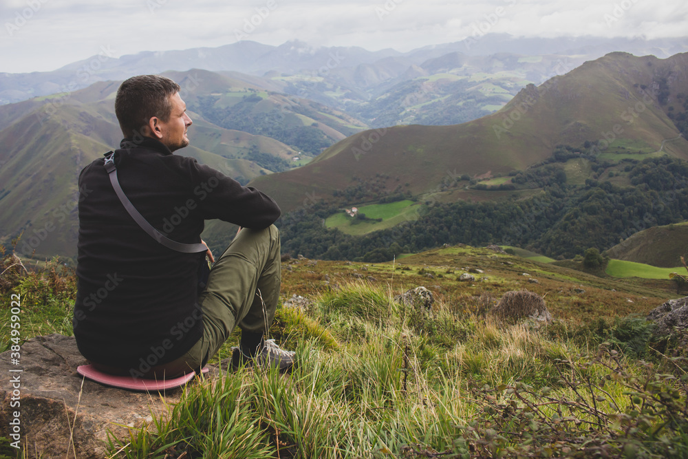 Man sitting on the top of Pyrenees mountains, France. Pause in travel. Tired pilgrim on Camino de Santiago. Lonely hiker in highlands. Active lifestyle. Freedom concept. Getting from it all concept. Man sitting on the top of Pyrenees mountains, France. Pause in travel. Tired pilgrim on Camino de Santiago. Lonely hiker in highlands. Active lifestyle. Freedom concept. Getting from it all concept.