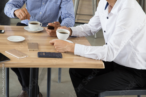 Two Asian businessmen discussing while having coffee together