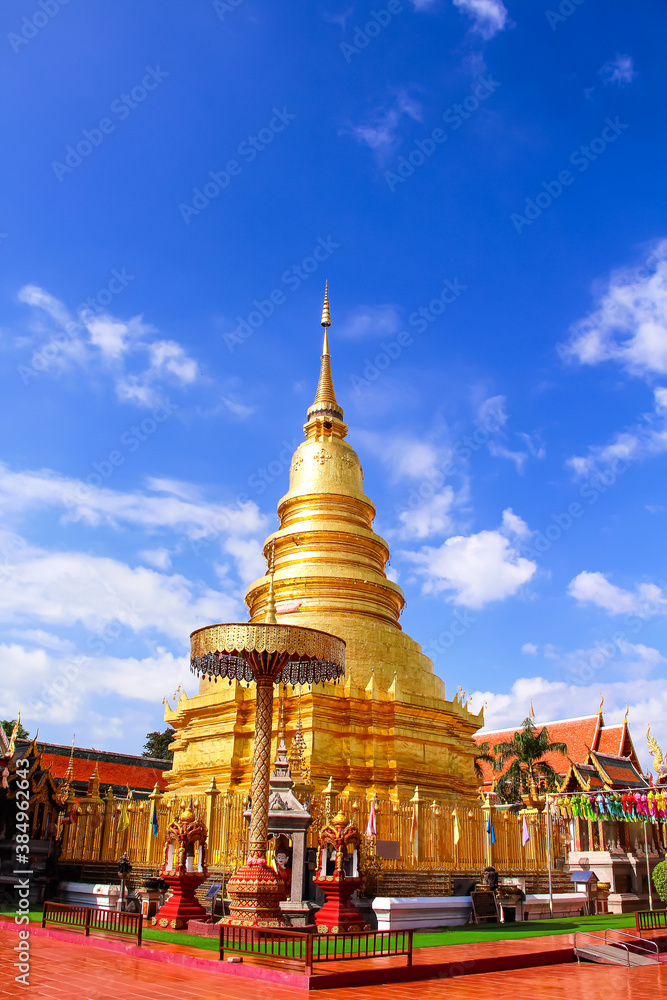 Fototapeta premium Ancient gold pagodaon bright blue sky background at Wat Phra That Hariphunchai woramahawihan in Lamphun of Thailand