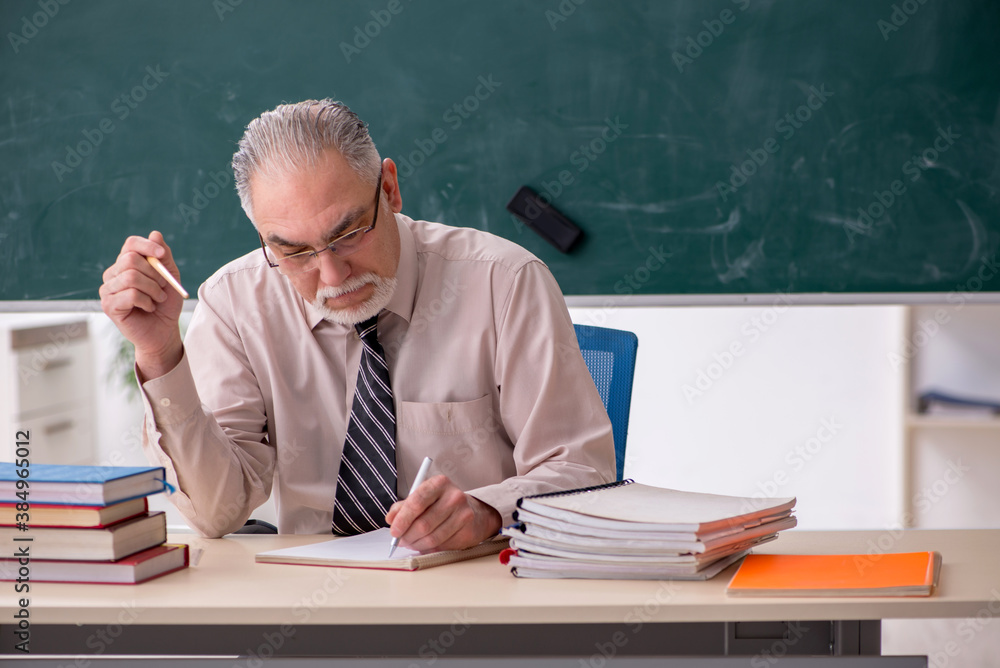 Old male teacher in the classroom Old male teacher in the classroom