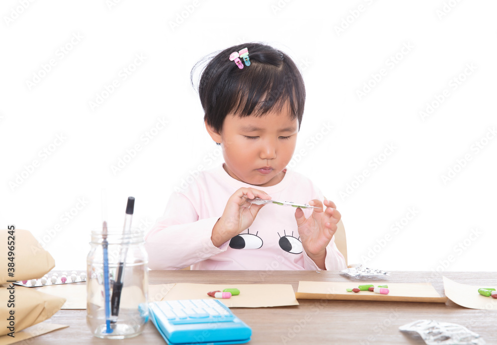 A little girl who plays a pharmacist in front of a white background is simulating dispensing medicine A little girl who plays a pharmacist in front of a white background is simulating dispensing medicine
