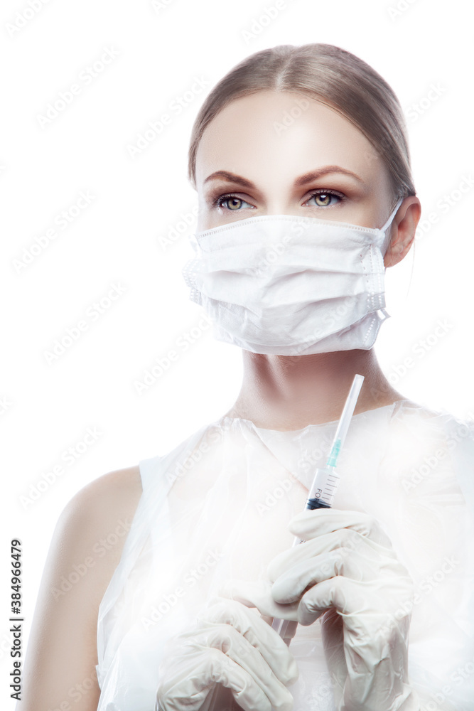 Beautiful young woman doctor prepae syringe with anti vius vaccine, wearng medical mask and gloves. Studio portrait. Health care concept