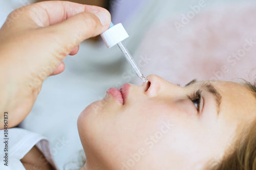 Young girl put drops into nose. Close up portrait of women with medicine